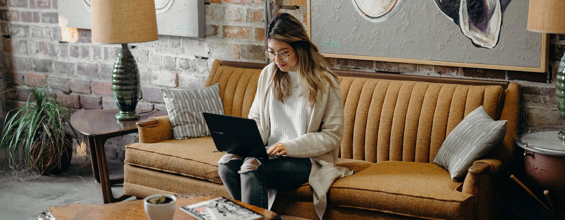 woman seating on a couch working on a laptop
